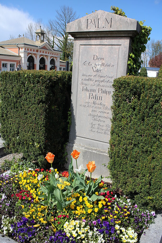 Der Grabstein und das Grab mit frischen Blumenschmuck auf dem Friedhof in Braunau am Inn.